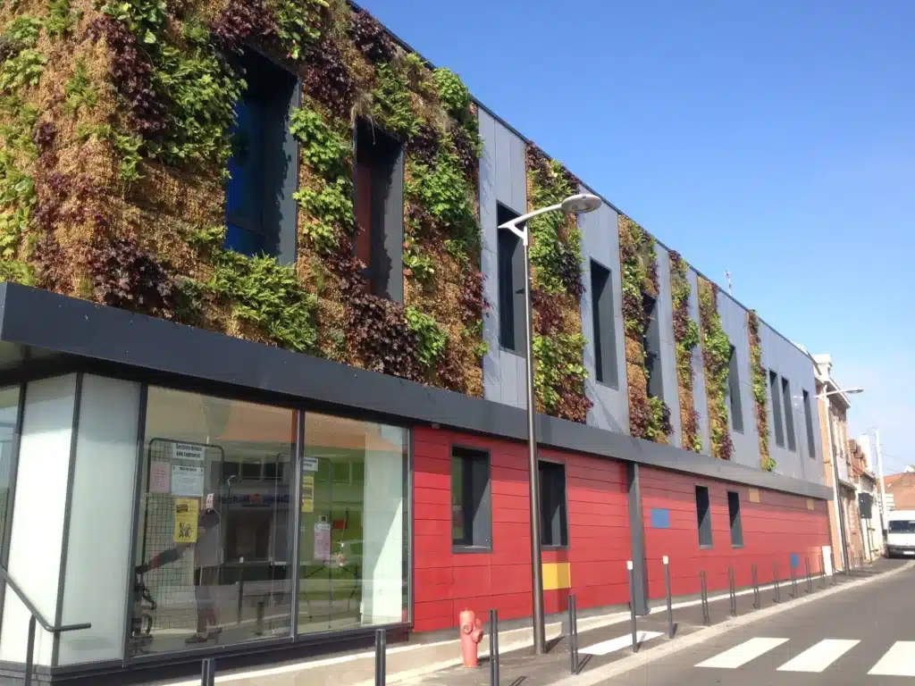 Façade du centre associatif de Barlin avec mur végétal et bardage rouge – ARCHIFIX